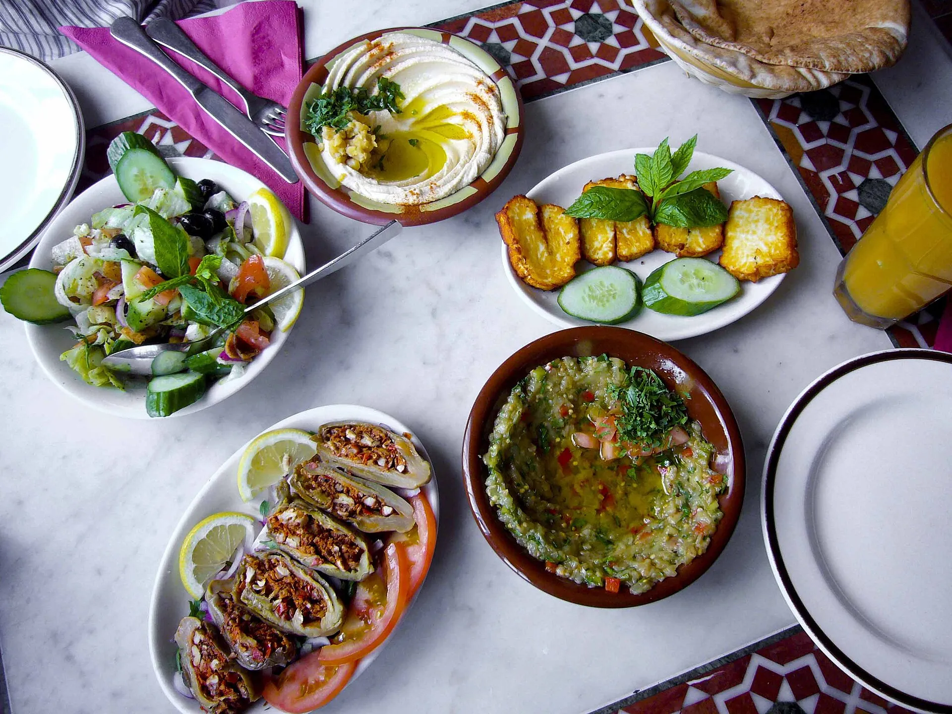 Gedeckter Tisch mit Hummus, Salat, Halloumi und weiteren Gerichten