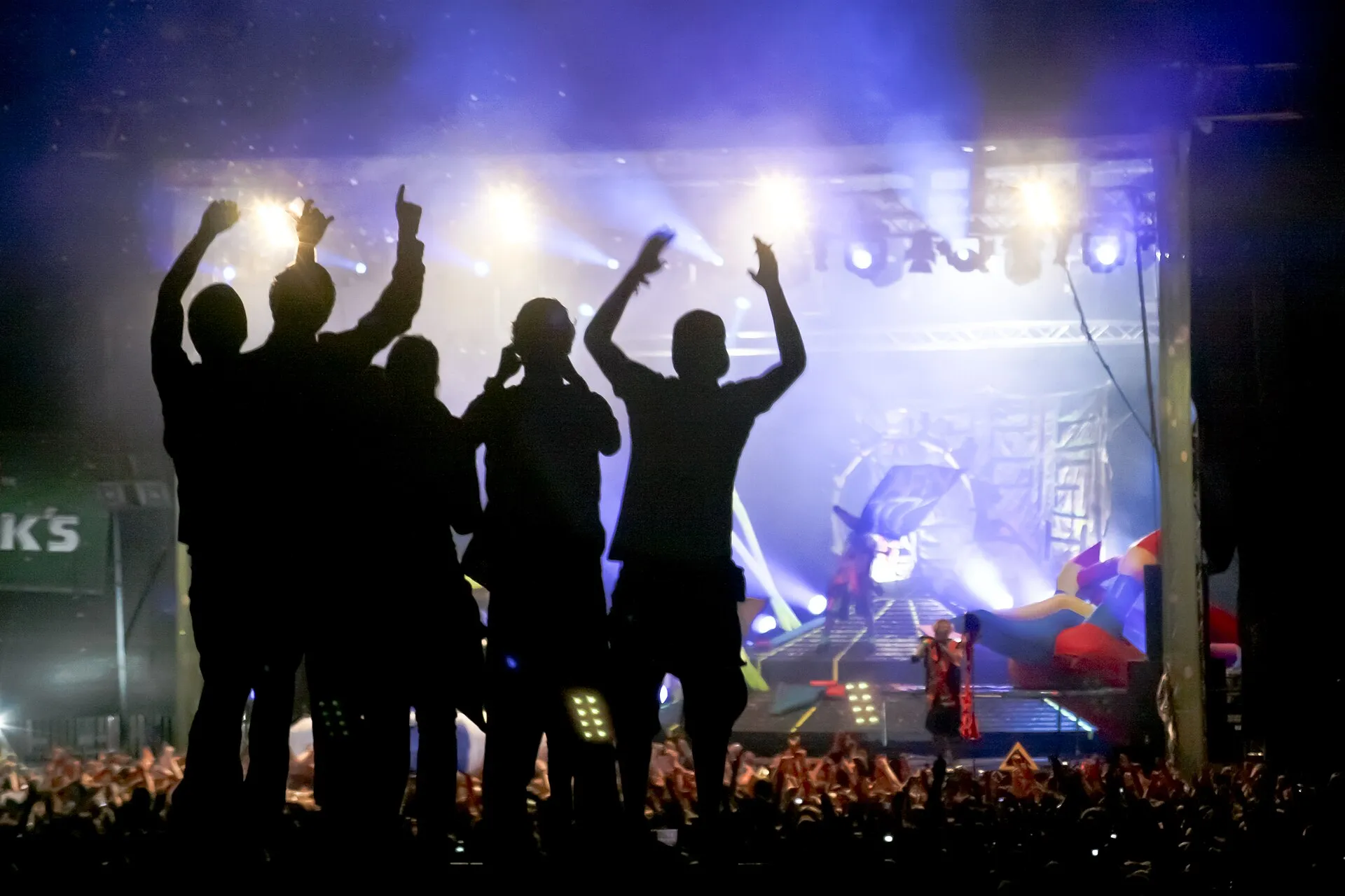 Silhouetten jubelnder Festivalbesucher vor beleuchteter Bühne beim Juicy Beats