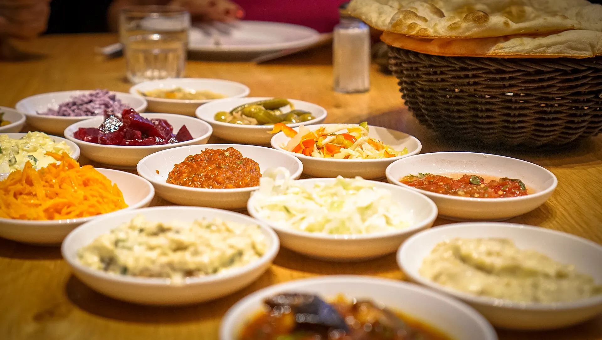 Viele kleine Schälchen mit Salaten und Dips auf Holztisch