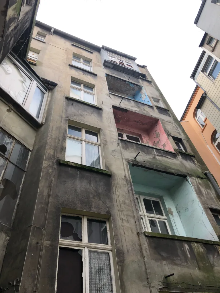 Rear facade seen from below, with balconies and broken windows