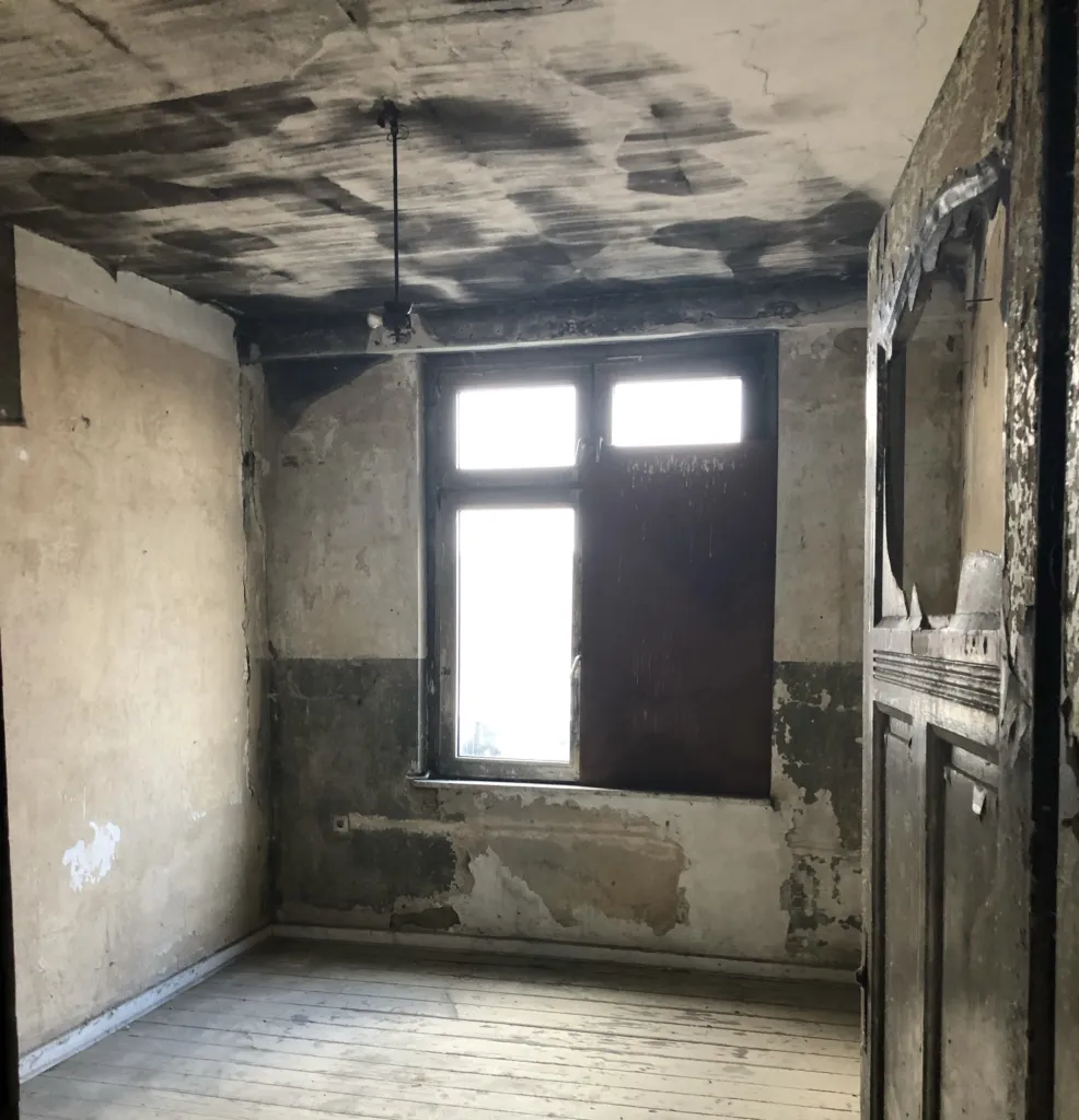 Vacant room with a sooty ceiling and crumbling plaster