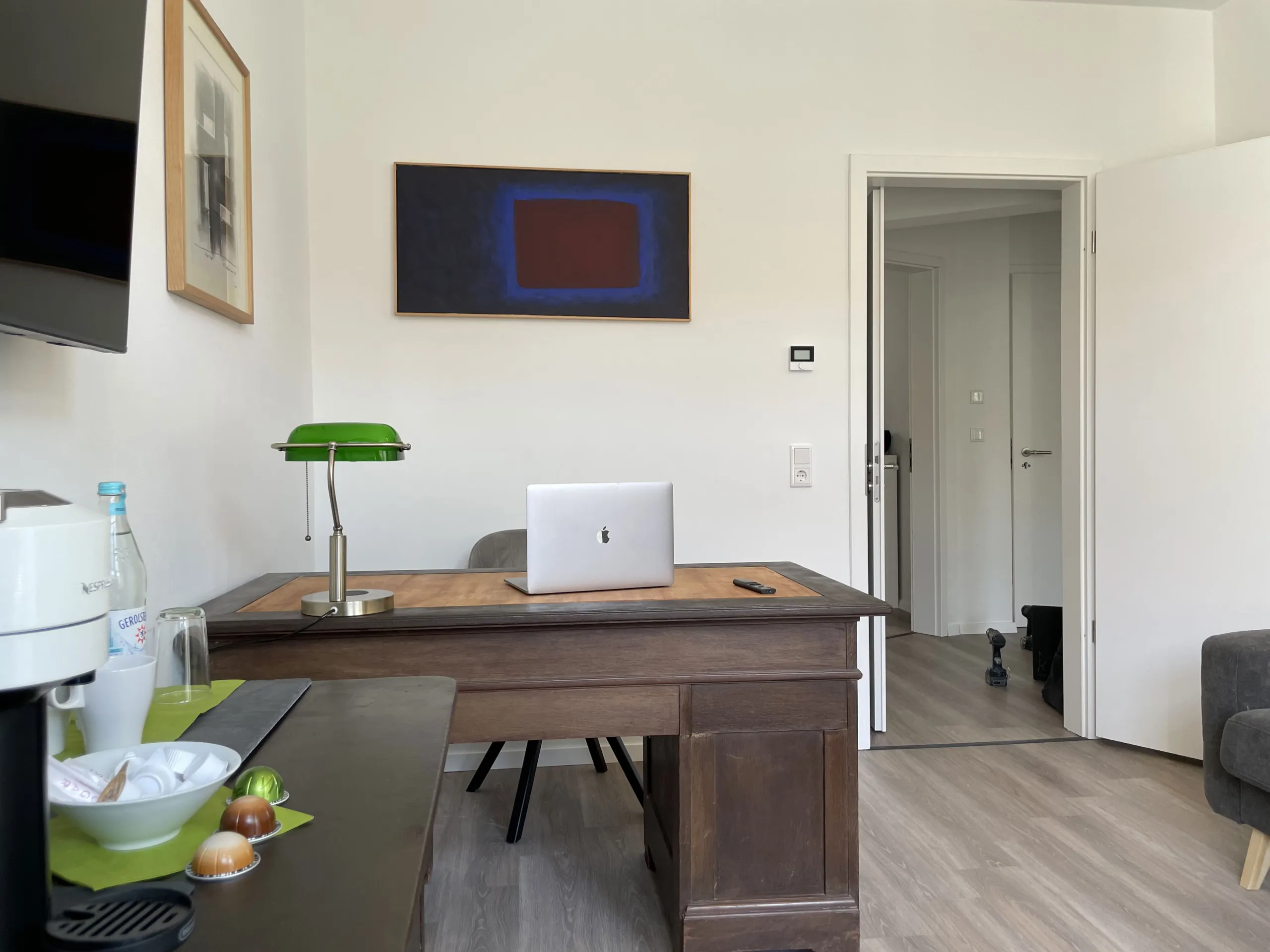 Desk with a laptop and a green reading lamp in the apartment