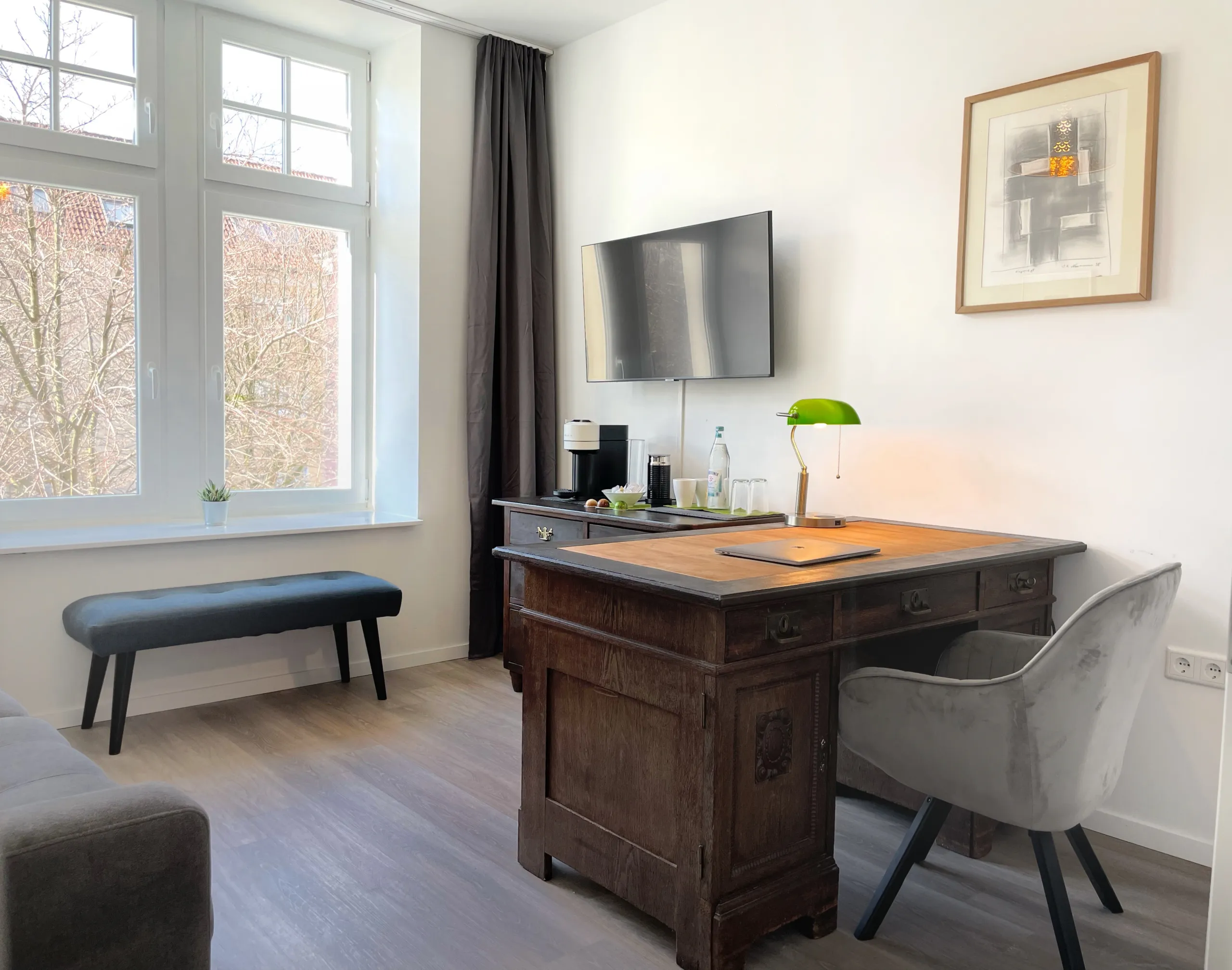 Workspace in the apartment: wooden desk with a green reading lamp by the window